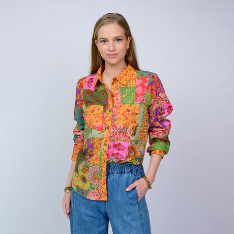 Woman wearing a colorful patchwork shirt against a plain background