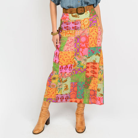 Person wearing a colorful patchwork skirt with a plain background