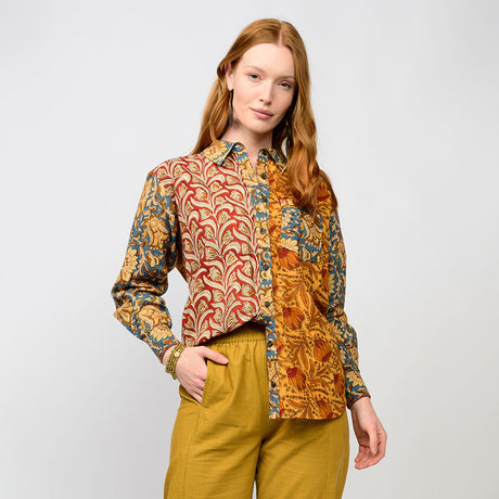 Woman wearing a patterned shirt and yellow pants on a plain background