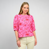Woman wearing a pink floral blouse against a gray background