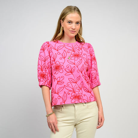 Woman wearing a pink floral blouse against a gray background