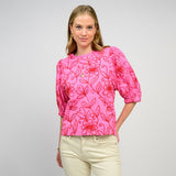 Woman wearing a pink floral blouse with a plain background