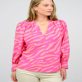 A woman wearing a pink modular zebra pattern blouse with three-quarter sleeves and a V-neckline.