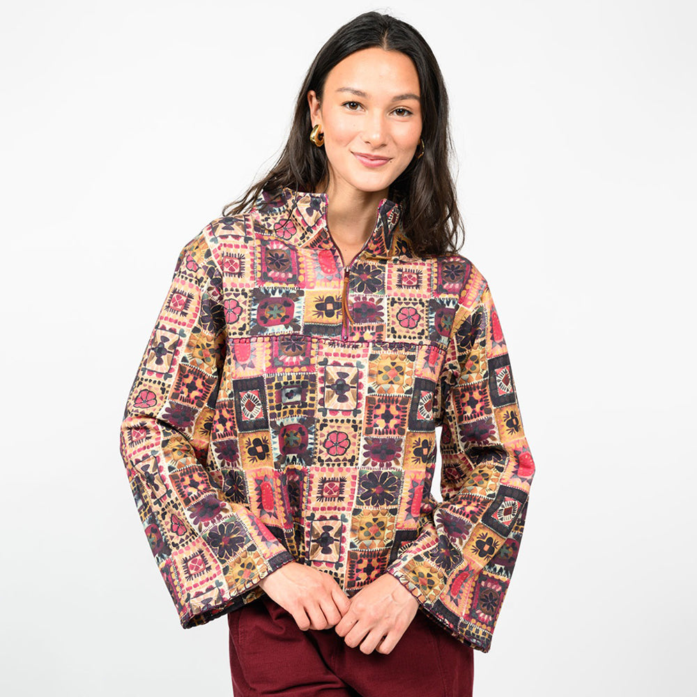a woman wearing a multi colored pullover  with burgundy pants