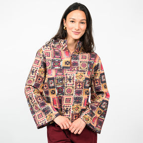 a woman wearing a multi colored pullover  with burgundy pants