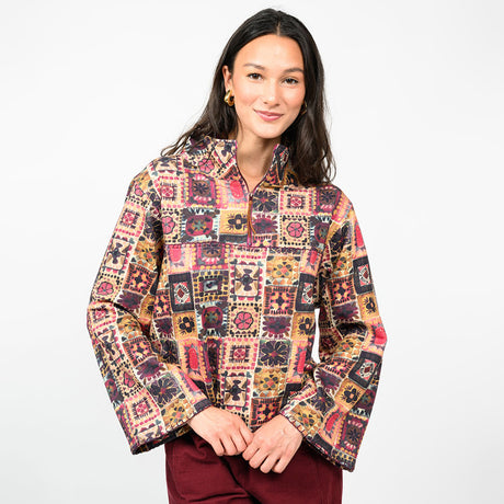 a woman wearing a multi colored pullover  with burgundy pants