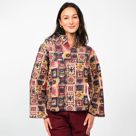 a woman wearing a multi colored pullover  with burgundy pants