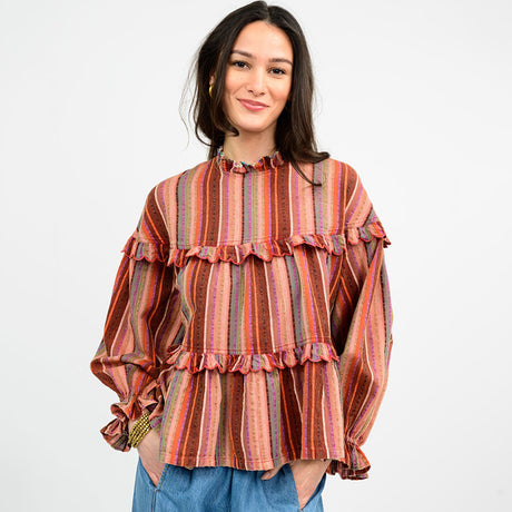 Woman wearing a colorful striped blouse with ruffled details on a white background