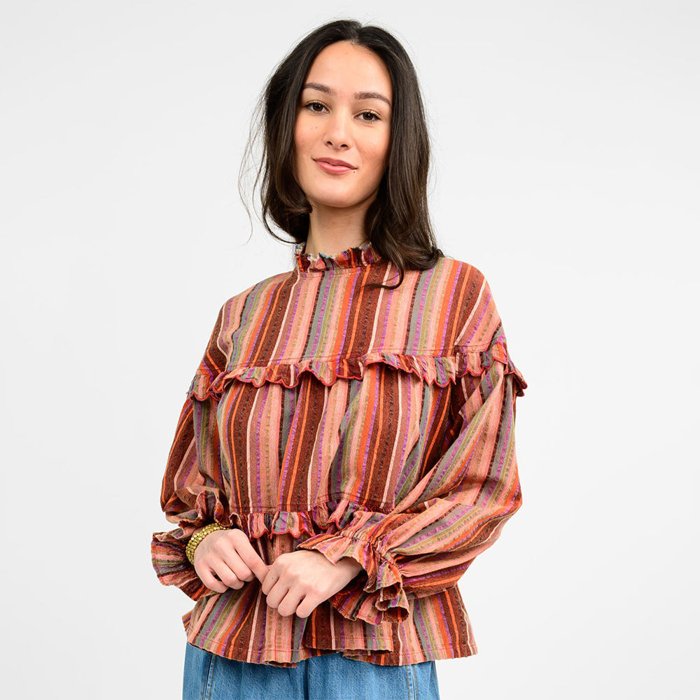 Woman wearing a striped blouse with ruffled details on a white background