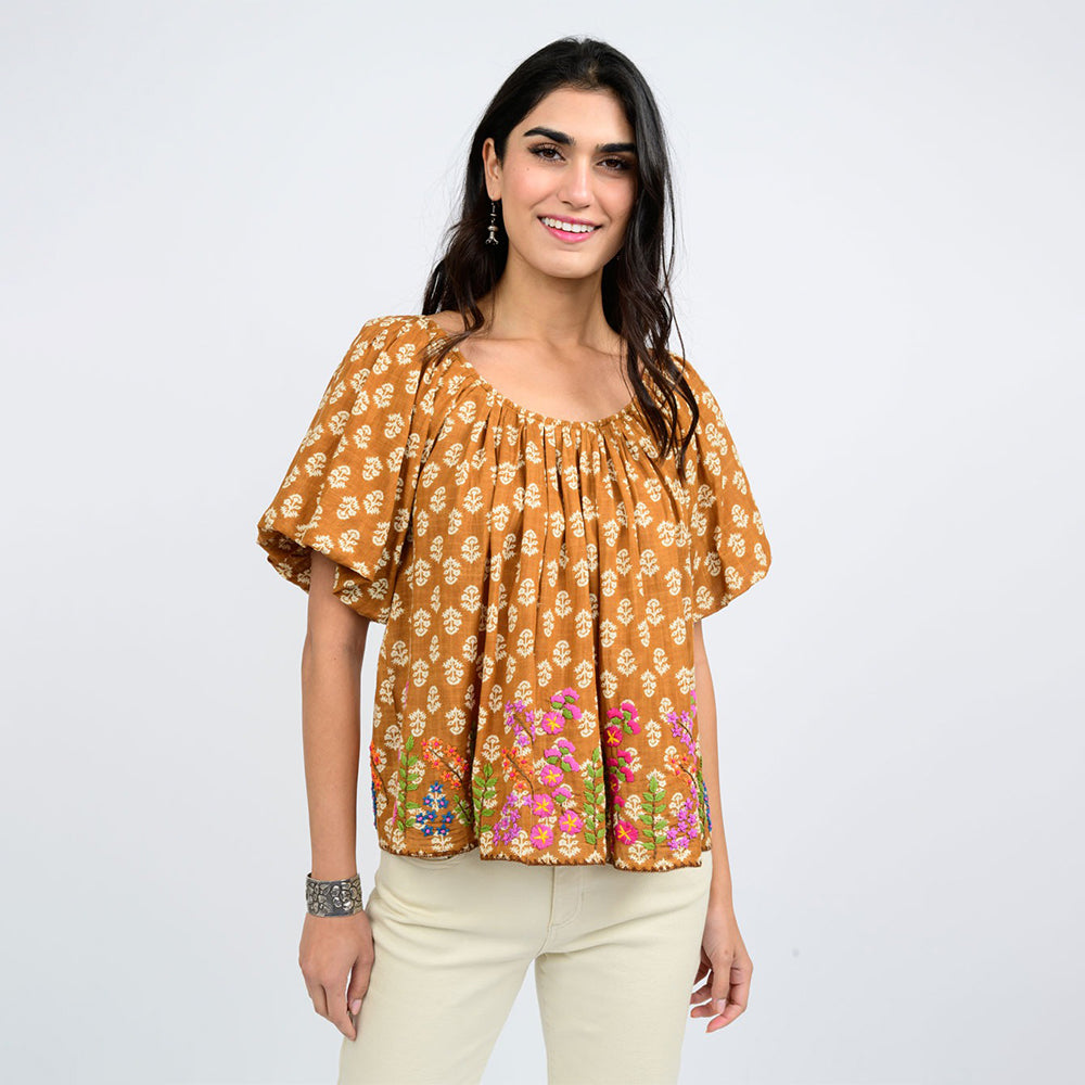 Woman wearing a orange floral blouse against a white background
