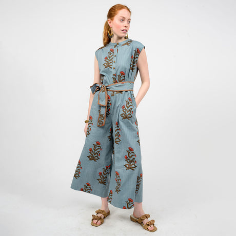 Woman wearing a blue jumpsuit with floral embroidery on a white background