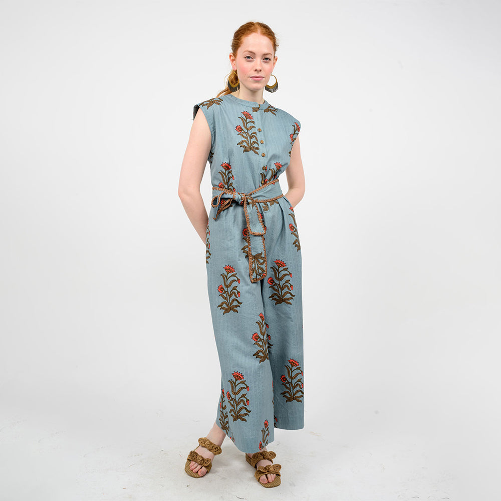 Woman wearing a blue jumpsuit with floral embroidery on a white background