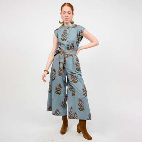 Woman wearing a blue jumpsuit with floral embroidery on a white background