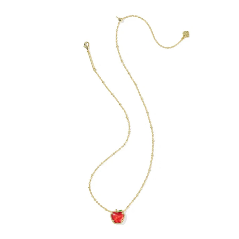 A delicate gold chain necklace featuring a small, heart-shaped red gemstone pendant with a tiny green accent at the top, displayed on a clean white background.