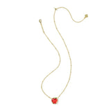A delicate gold chain necklace featuring a small, heart-shaped red gemstone pendant with a tiny green accent at the top, displayed on a clean white background.