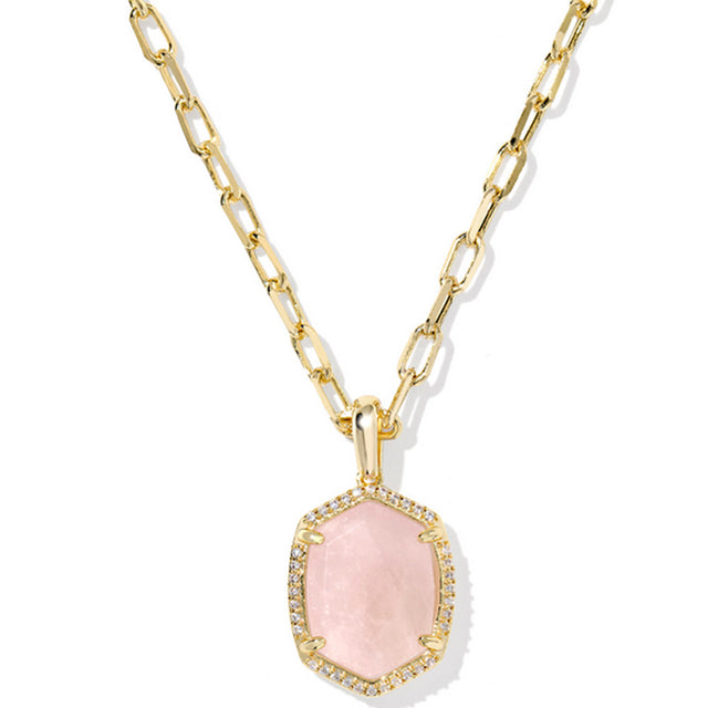 Gold necklace with a pink pendant on a white background