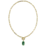 A gold paperclip chain necklace with a toggle clasp and a small oval green gemstone pendant, shown on a plain white background.