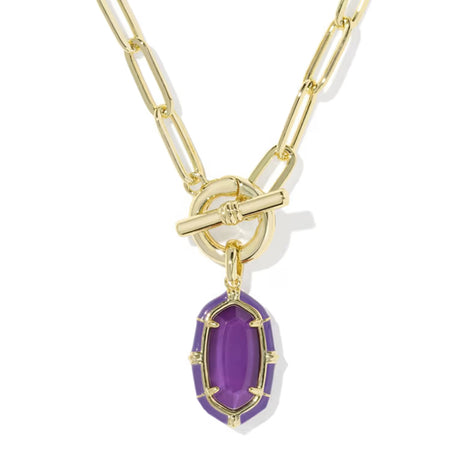 A gold paperclip chain necklace with a toggle clasp and a dangling purple faceted gemstone pendant, shown on a clean white background.