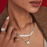 A close-up lifestyle shot of a model wearing layered silver necklaces, including a curved bar necklace, a delicate chain with a butterfly pendant, and a thin chain with a pearl accent, along with matching butterfly rings.