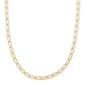 A gold Figaro chain necklace with elongated oval links, displayed in a curved shape against a solid white background.