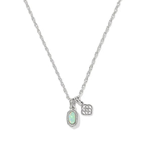 A silver chain necklace featuring an oval pendant with a light green opal-like center surrounded by small clear stones, alongside a small geometric charm, shown on a plain white background.