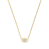 A delicate gold chain necklace featuring an oval pendant with a small clear central stone surrounded by a halo of tiny clear stones, set against a plain white background.