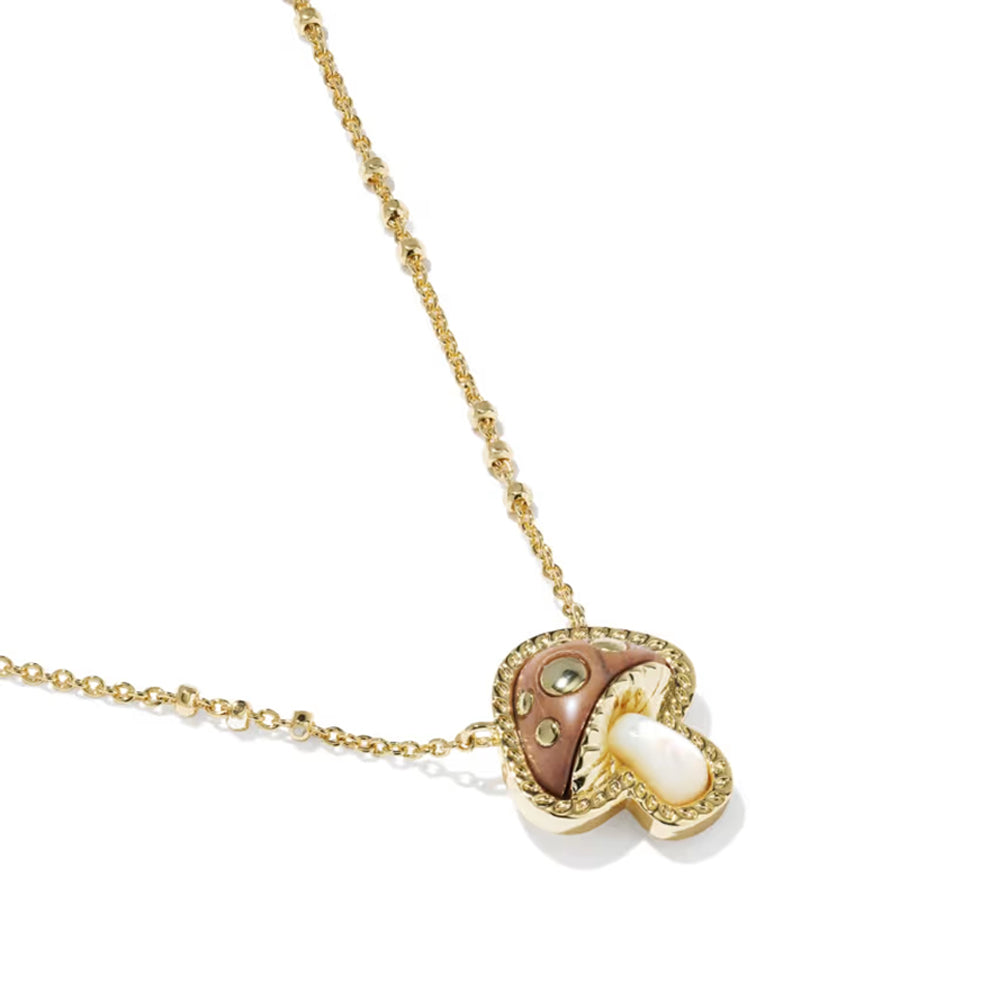 A gold necklace with a mushroom-shaped pendant featuring a brown inlay, a white pearl-like center, and small clear stones, shown on a white background.