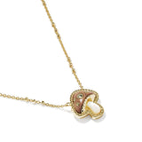 A gold necklace with a mushroom-shaped pendant featuring a brown inlay, a white pearl-like center, and small clear stones, shown on a white background.