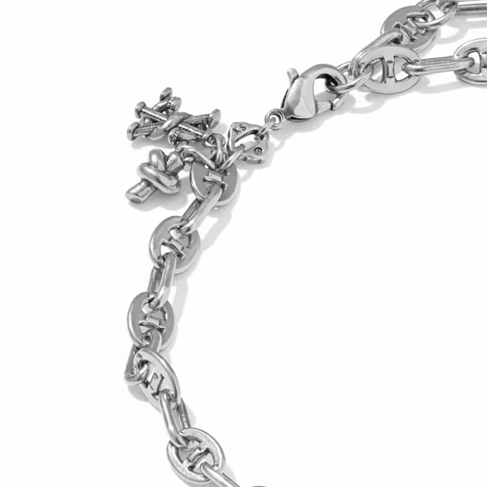 A close-up of a silver chain bracelet featuring a small cross charm and a heart-shaped accent, set against a plain white background.