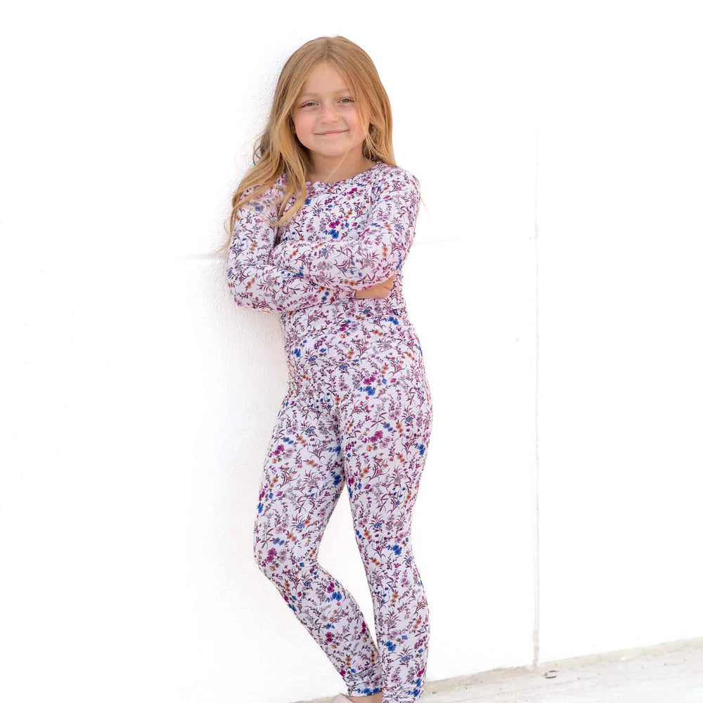 Young girl wearing a floral pajama set against a white background