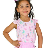 A young girl with braided hair wearing a light pink short-sleeve top with a mermaid and sea life print, paired with a matching pink skirt, against a plain white background.