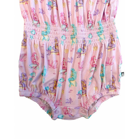 A pink baby romper with an all-over mermaid and sea life print, featuring a smocked waist and ruffled trim.