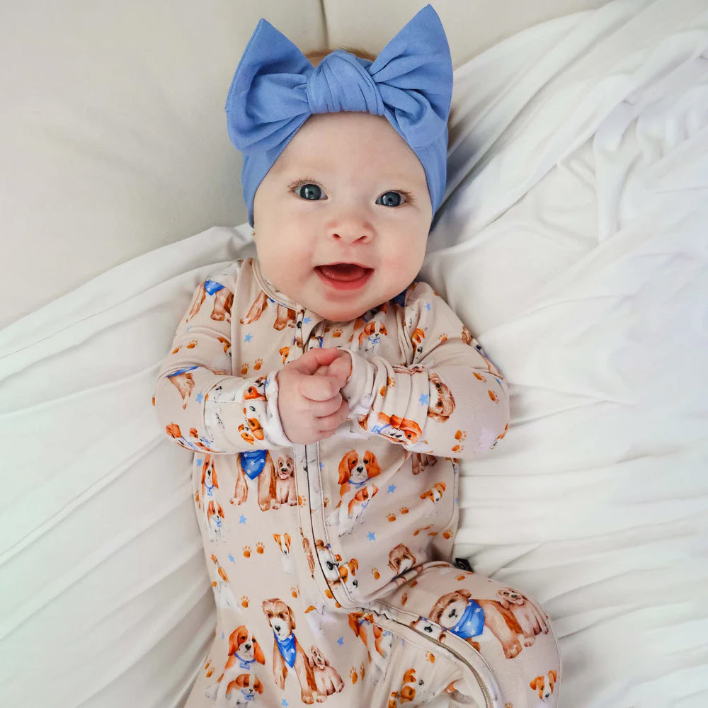Baby wearing a blue headband on a white blanket