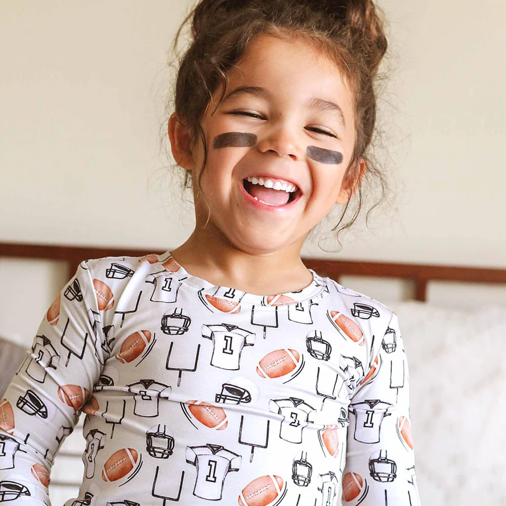 Child wearing a sports-themed pajamas with face paint, smiling