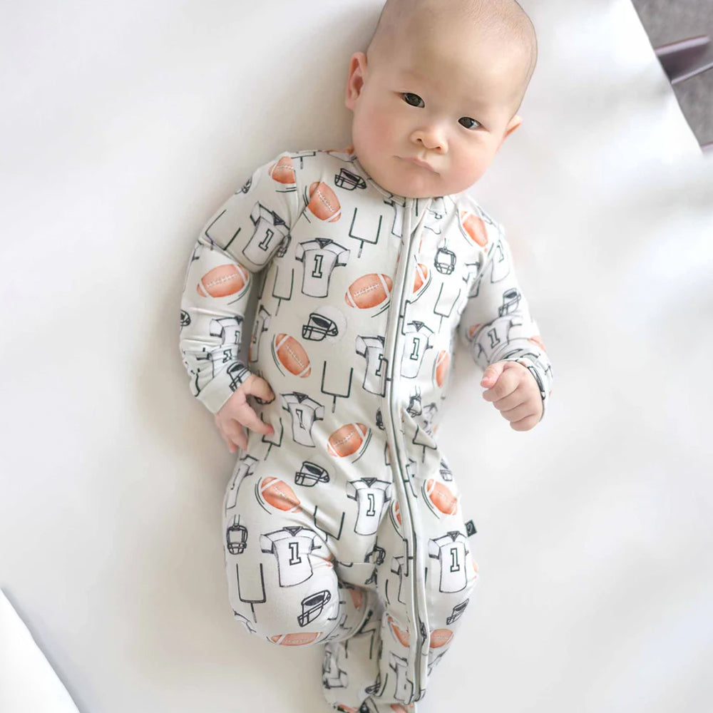 Baby wearing a patterned onesie lying on a white surface