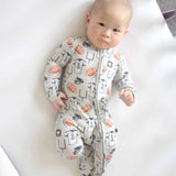 Baby wearing a patterned onesie lying on a white surface