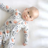 Baby wearing a onesie with sports-themed print on a white background