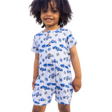 Child wearing a white romper with blue car pattern outdoors