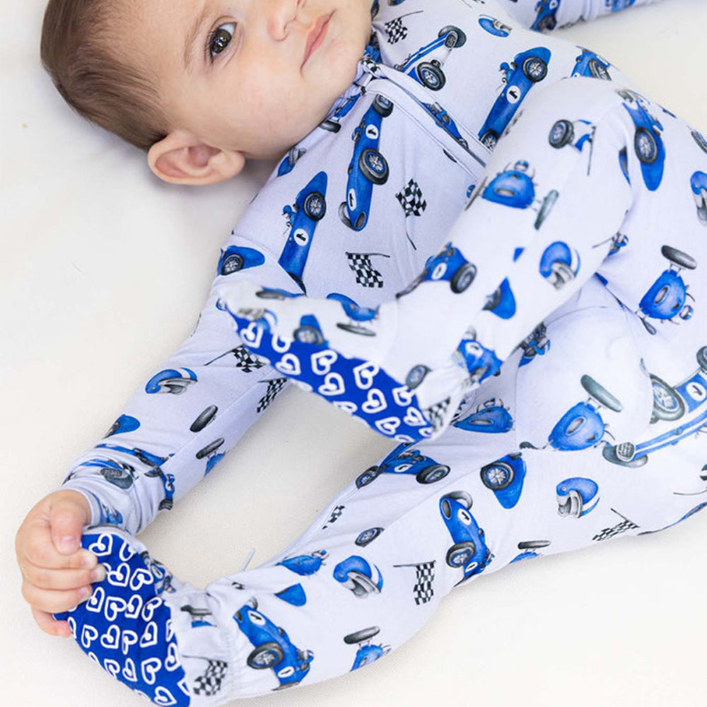 Baby wrapped in a car-themed swaddle blanket on a white background