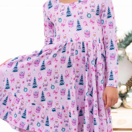 Pink dress with Christmas-themed pattern worn by a person, with a blurred background.
