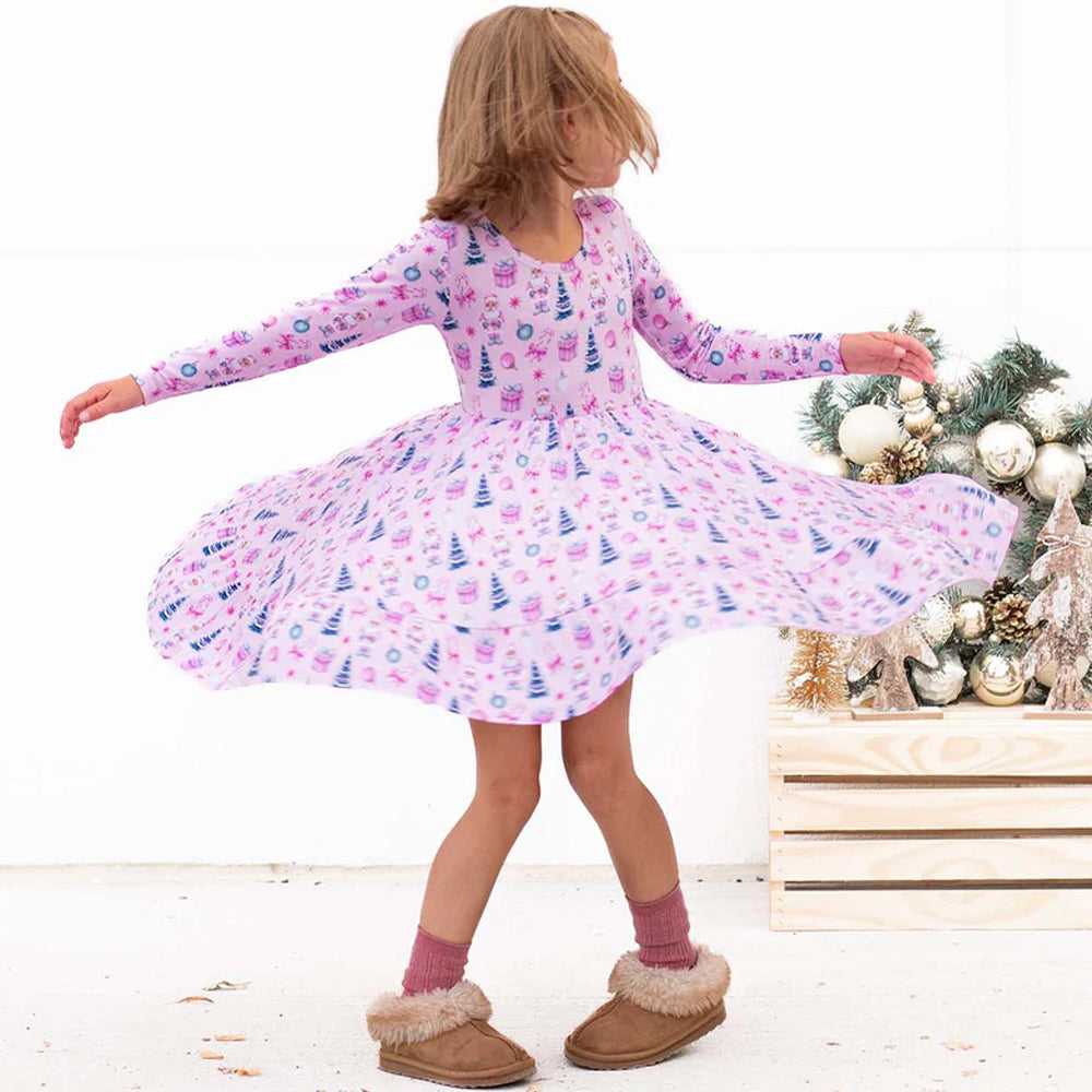 Child in a pink dress with a Christmas tree in the background