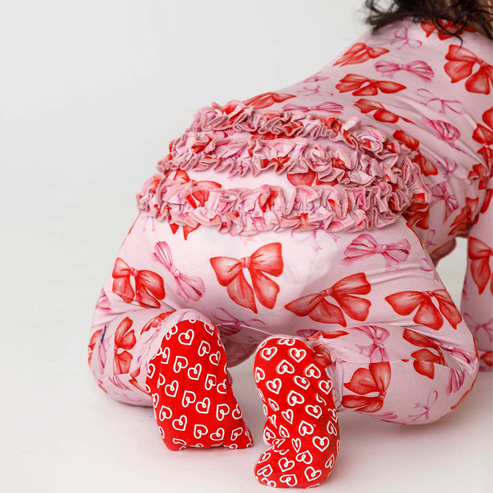 Child wearing a pink outfit with red bows and heart patterns on a white background