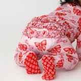 Child wearing a pink outfit with red bows and heart patterns on a white background