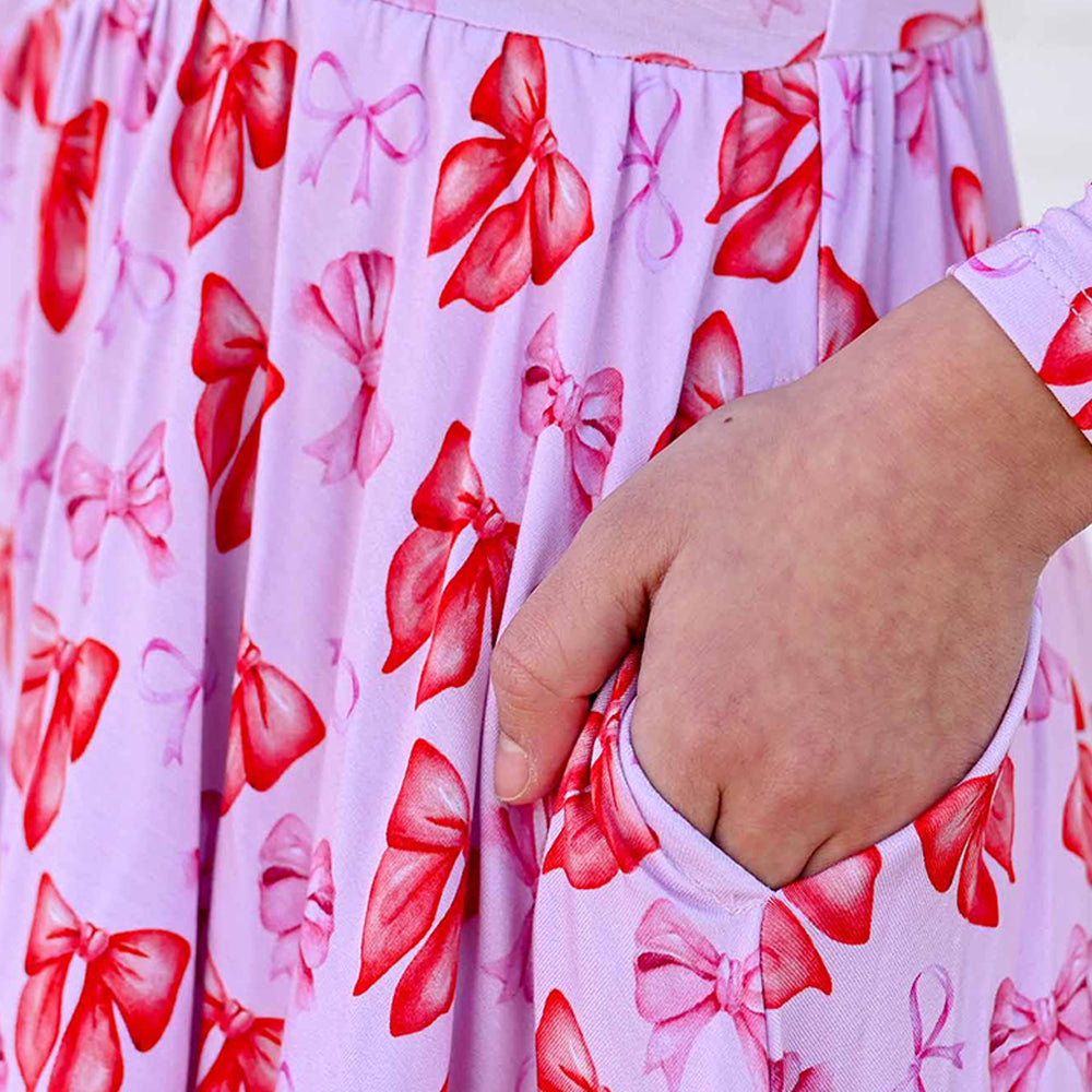Close-up of a hand holding a pink fabric with red bow pattern
