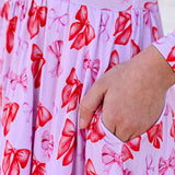 Close-up of a hand holding a pink fabric with red bow pattern
