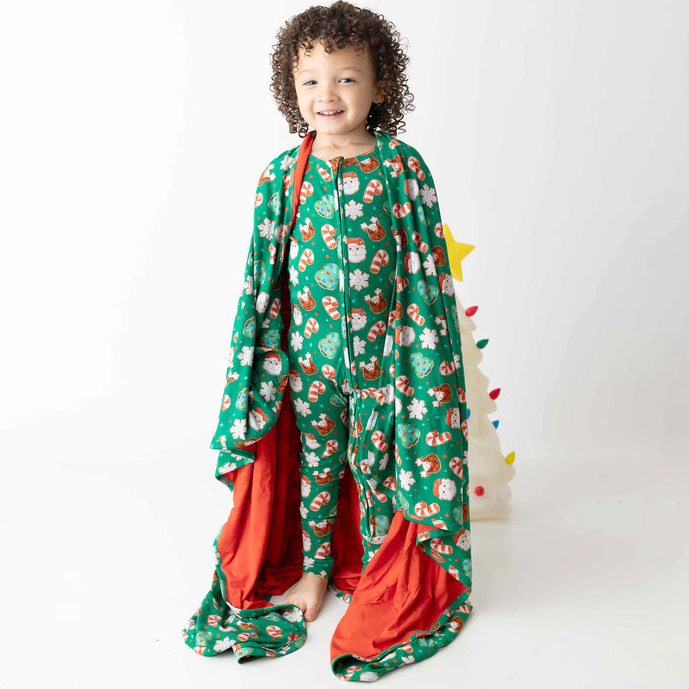 Child wearing a green patterned outfit with red accents on a white background