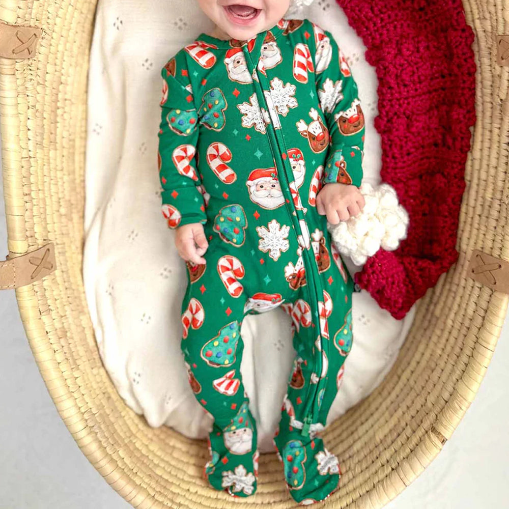 Baby in a festive green onesie with Santa Claus and candy cane pattern, sitting in a woven basket.