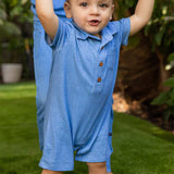 Child wearing a blue outfit with buttons outdoors on grass
