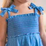 Close-up of a blue dress with bow straps worn by a child.