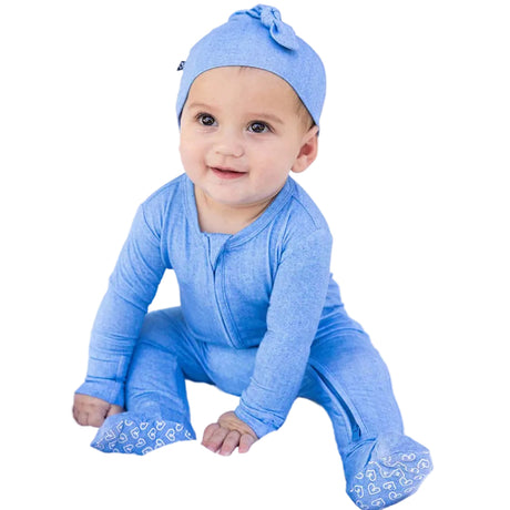 Baby wearing a blue outfit and hat sitting on a white surface